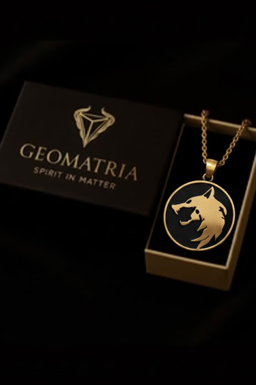 a gold pendant with a wolf's head design, displayed in a black box with the text "Geomatria Spirit in Matter" printed on it.