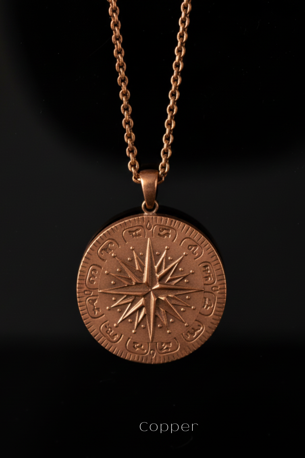 A copper-colored pendant necklace with a round medallion featuring a compass design.