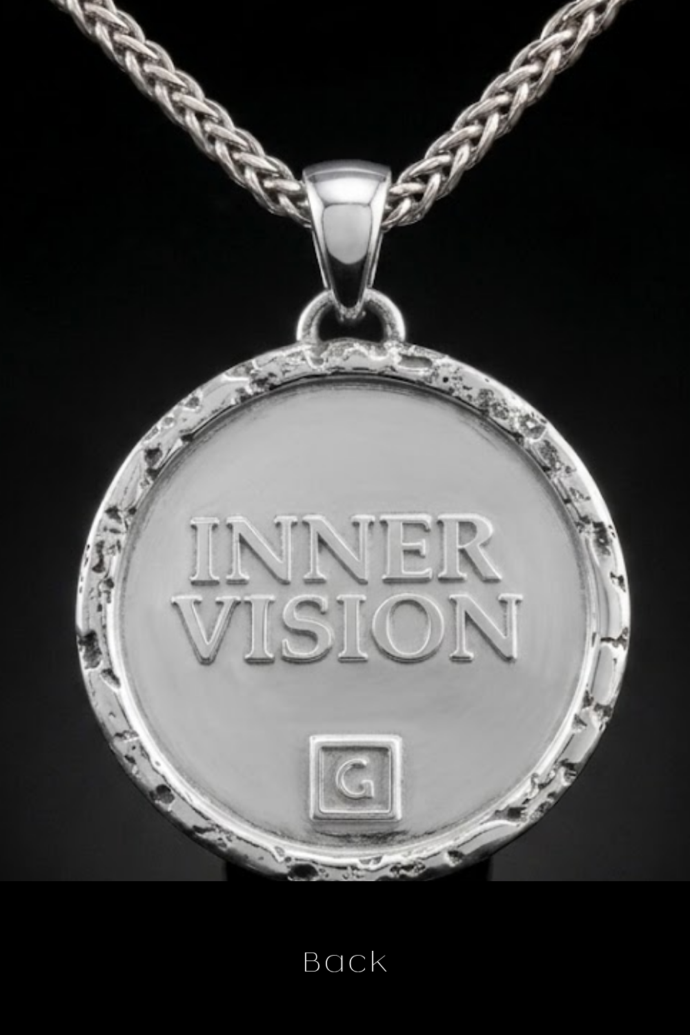 A silver-colored pendant necklace with the text "INNER VISION" engraved on it.