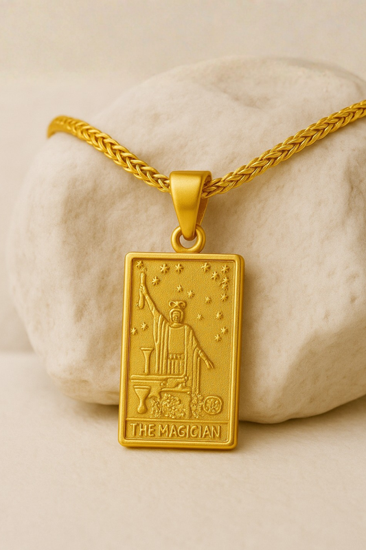 A gold-colored pendant necklace with a rectangular pendant featuring an illustration of a tarot card, specifically "The Magician".