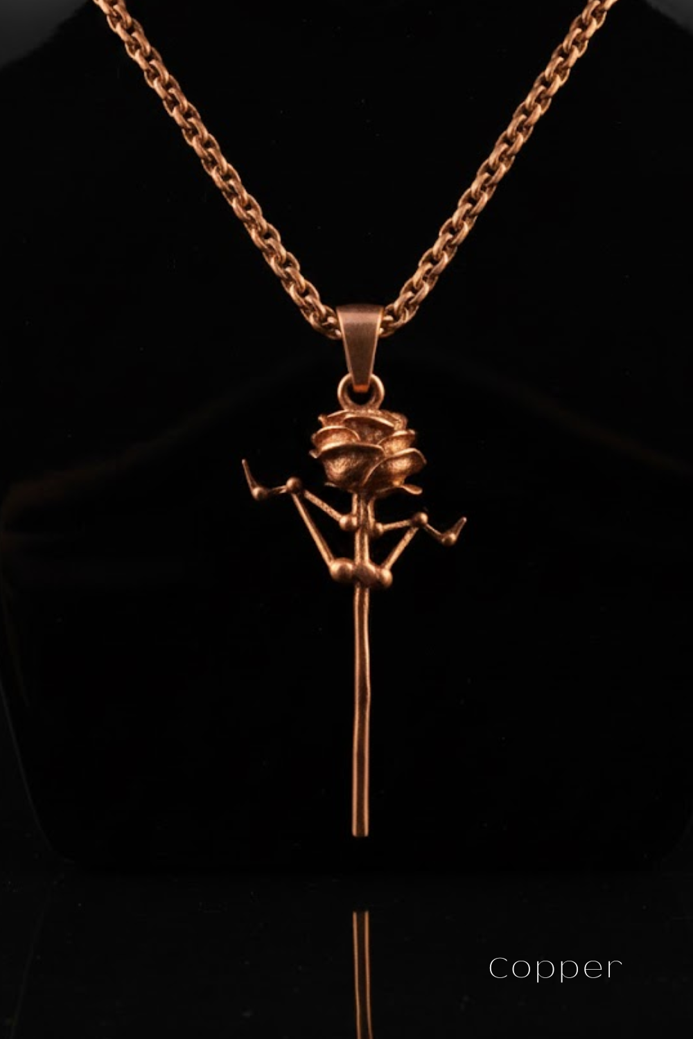 A copper-colored pendant necklace with a unique, abstract design featuring a stylized figure or symbol.