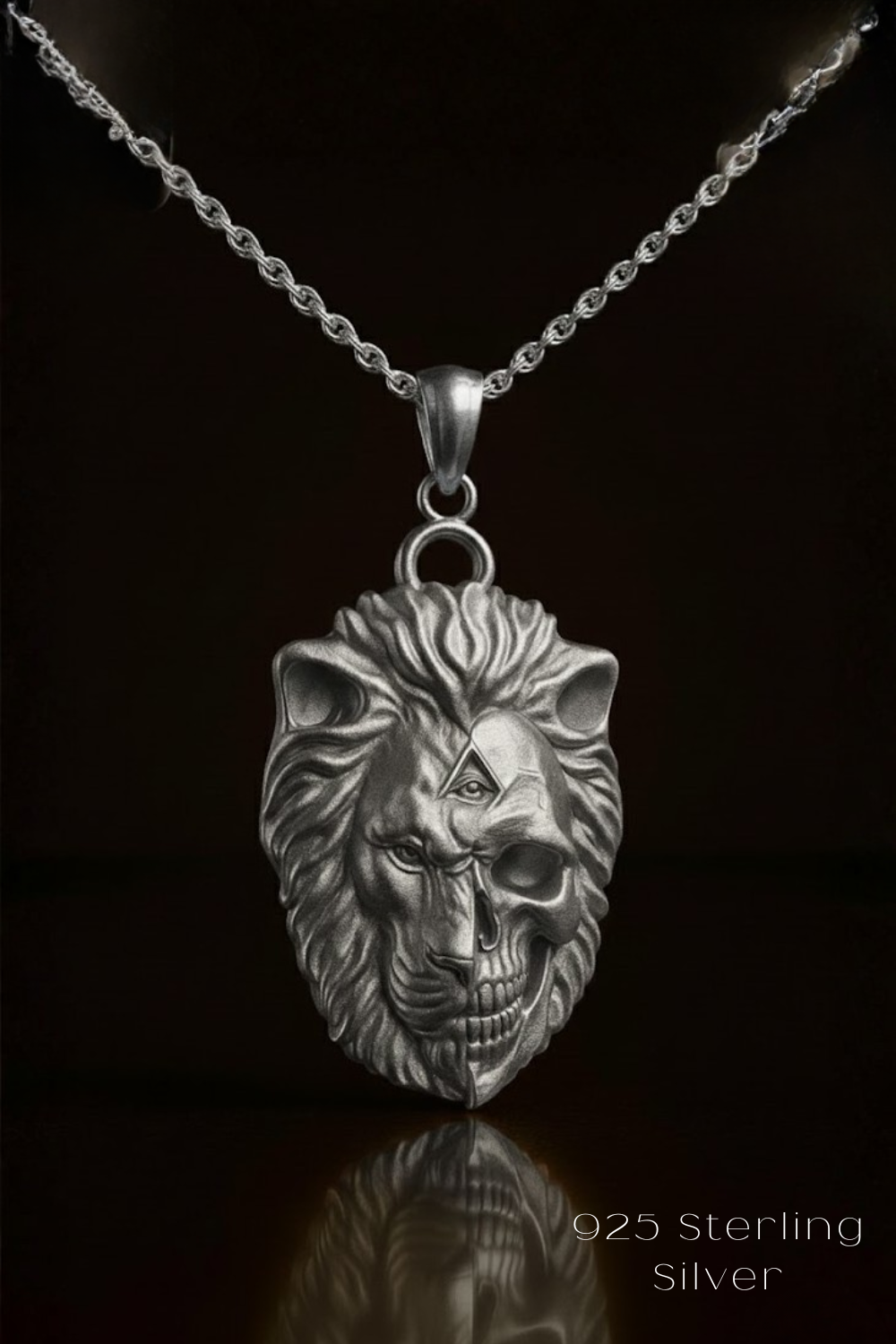 A silver pendant necklace with a detailed lion's head design and a skull-like face on the front.