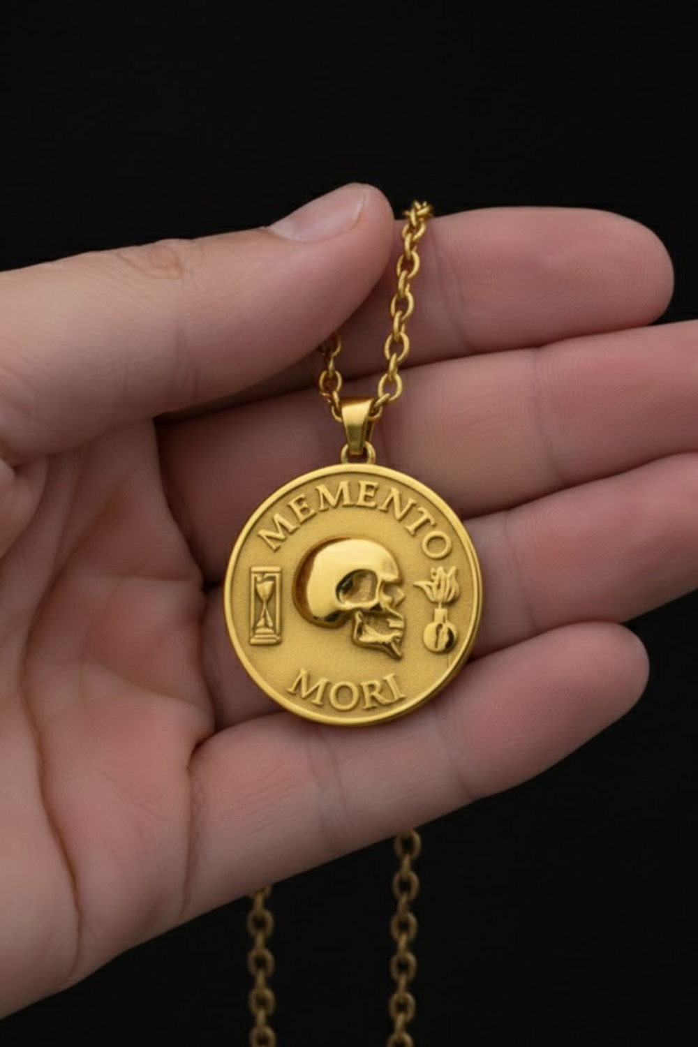 A gold-colored pendant necklace with a medallion featuring a skull and the Latin phrase "MEMENTO MORI" (Memento mori) engraved on it.
