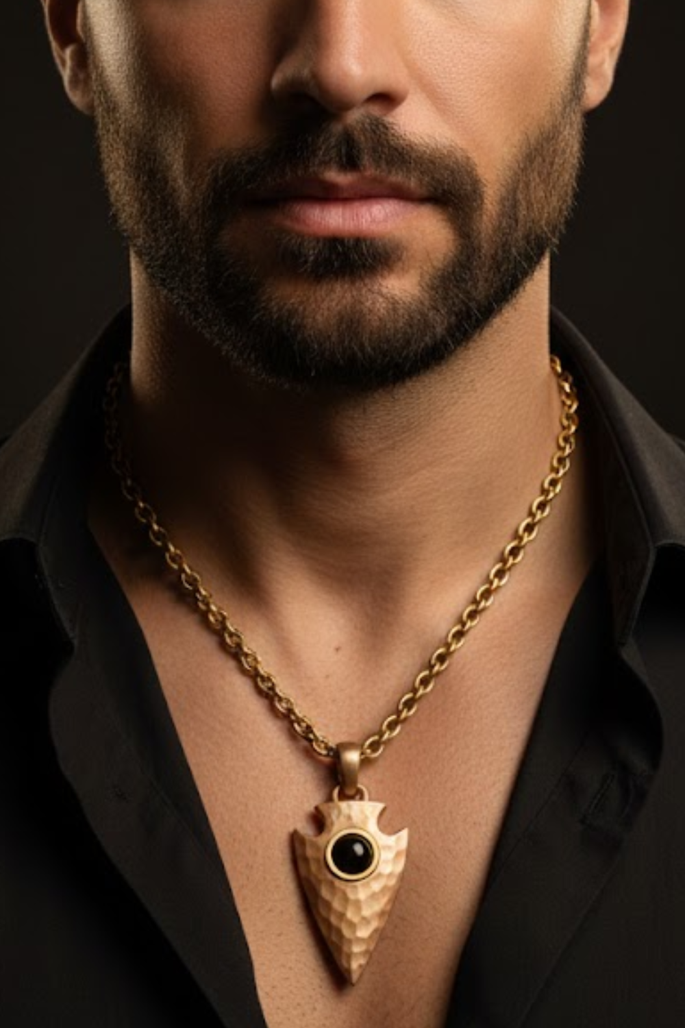 A close-up of a man's neck and chest area, with a gold chain necklace and a pendant featuring a black stone or gemstone.