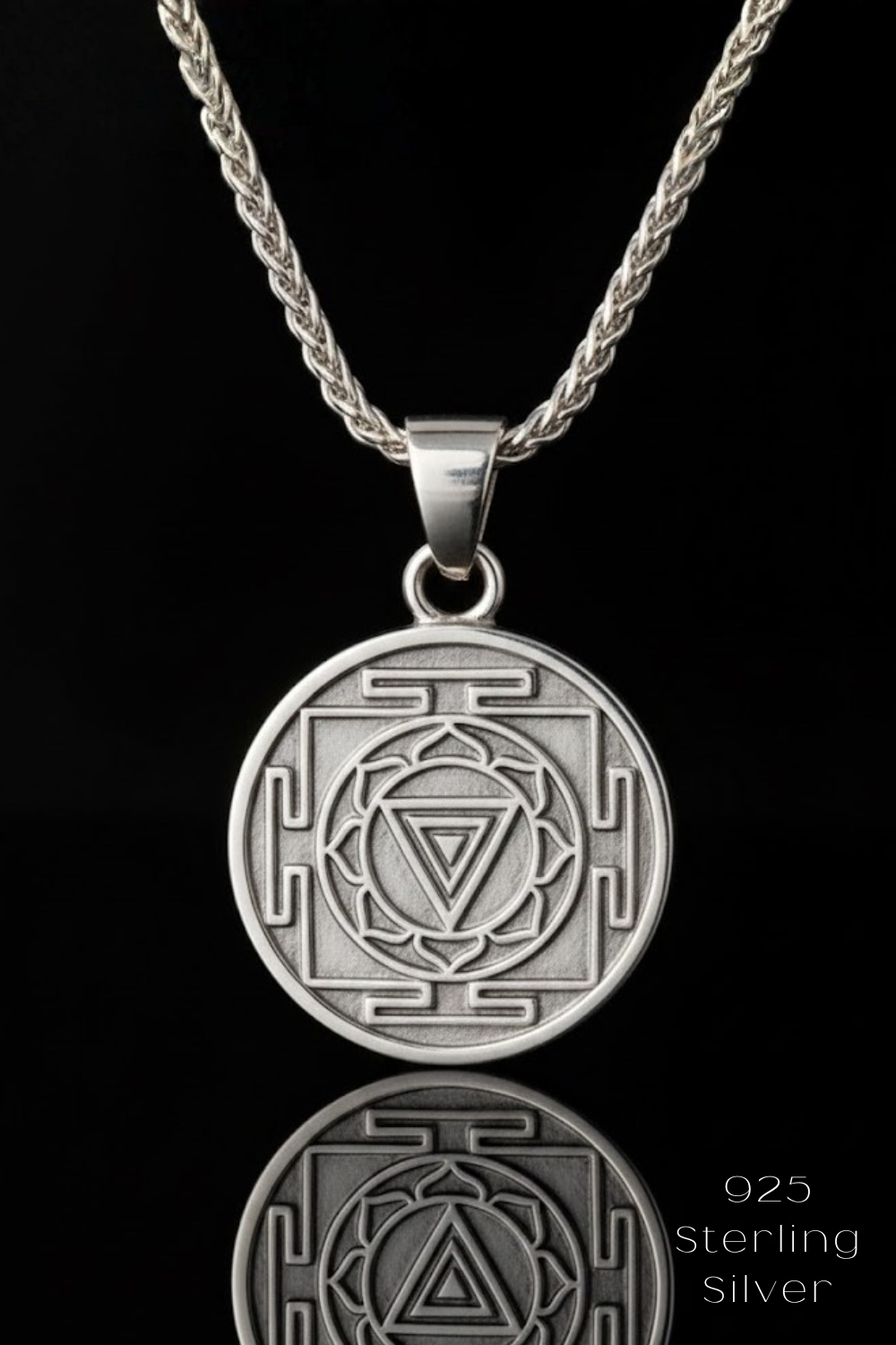 A silver pendant necklace with a circular medallion featuring a geometric design.