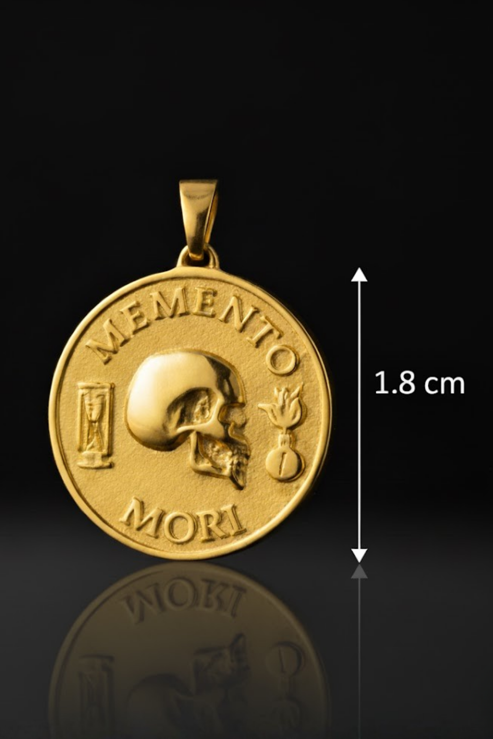 a gold-colored pendant with the text "MEMENTO MORI" and a skull design, along with a small hourglass and a candle. The pendant is shown against a black background, and there is a measurement scale indicating its size.