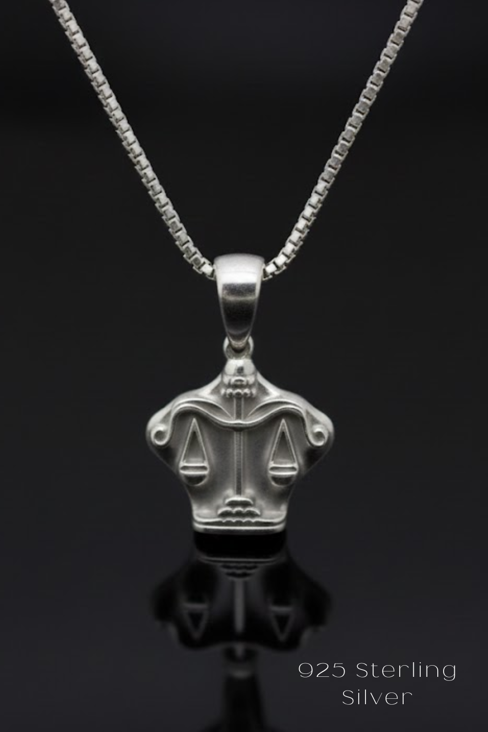A silver-colored pendant necklace with a design featuring scales of justice.