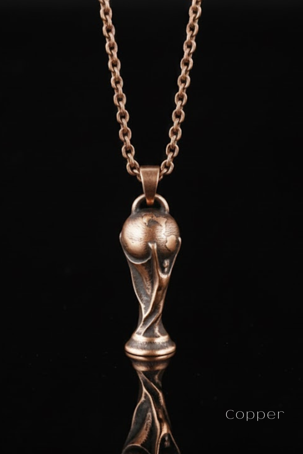A copper-colored pendant necklace with a unique, sculpted trophy-like design.