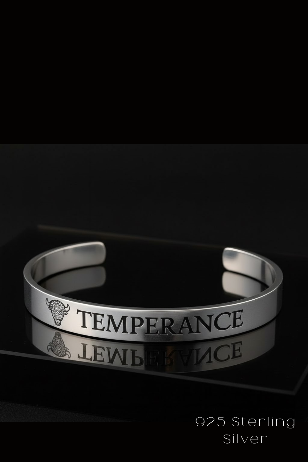 A silver bracelet with the word "TEMPERANCE" engraved on it, placed on a reflective surface against a black background.