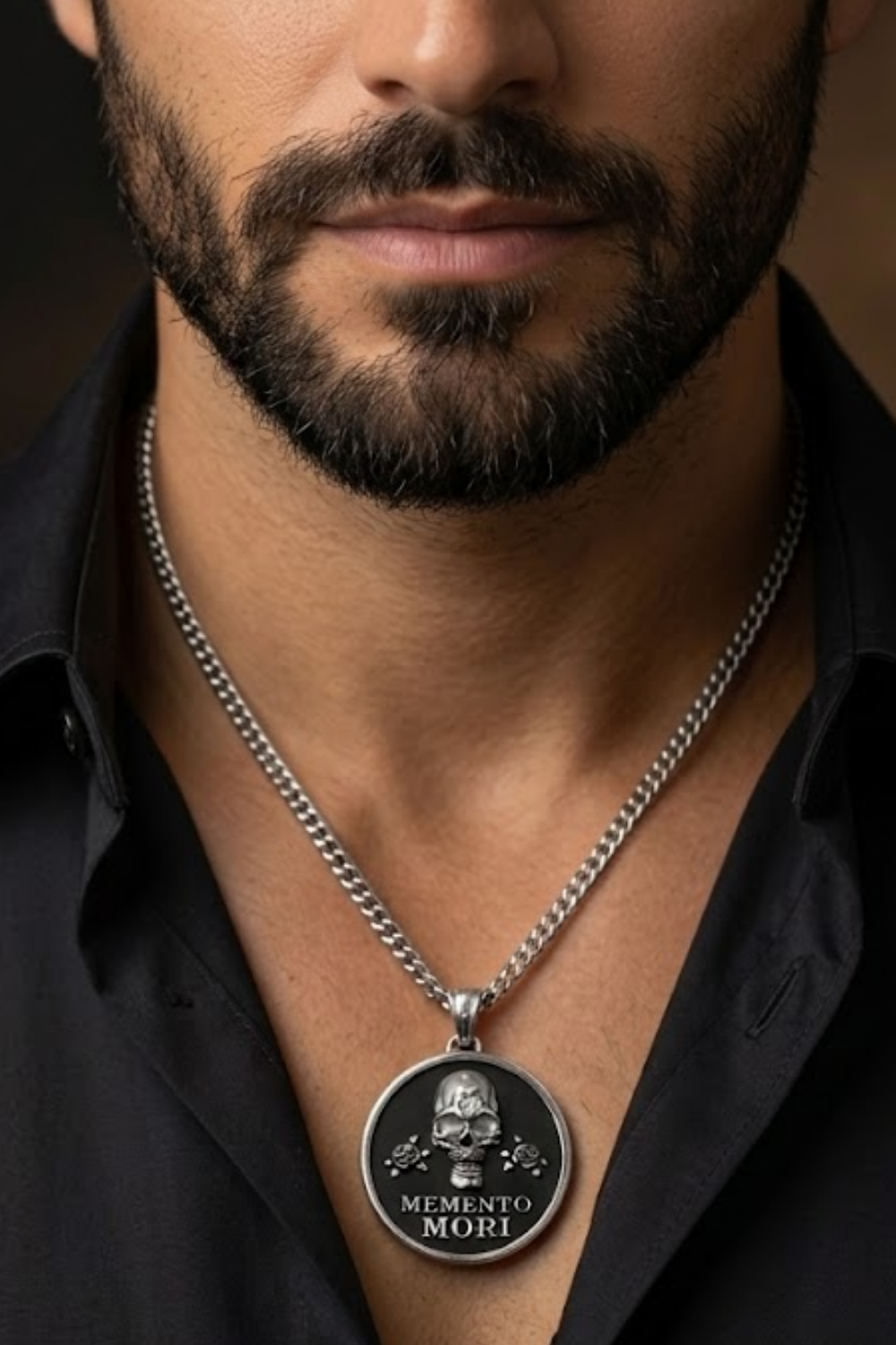 A close-up of a man's neck and chest area, with a silver necklace featuring a pendant with a skull and the text "Memento mori" (The Way of the Dead) on it.