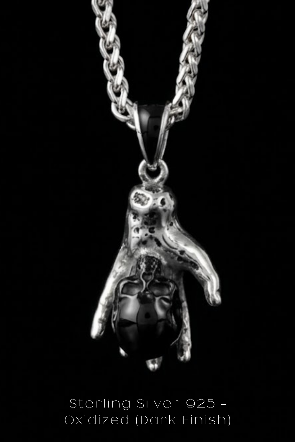 A silver pendant necklace with a black stone or gemstone in the center, suspended from a chain.