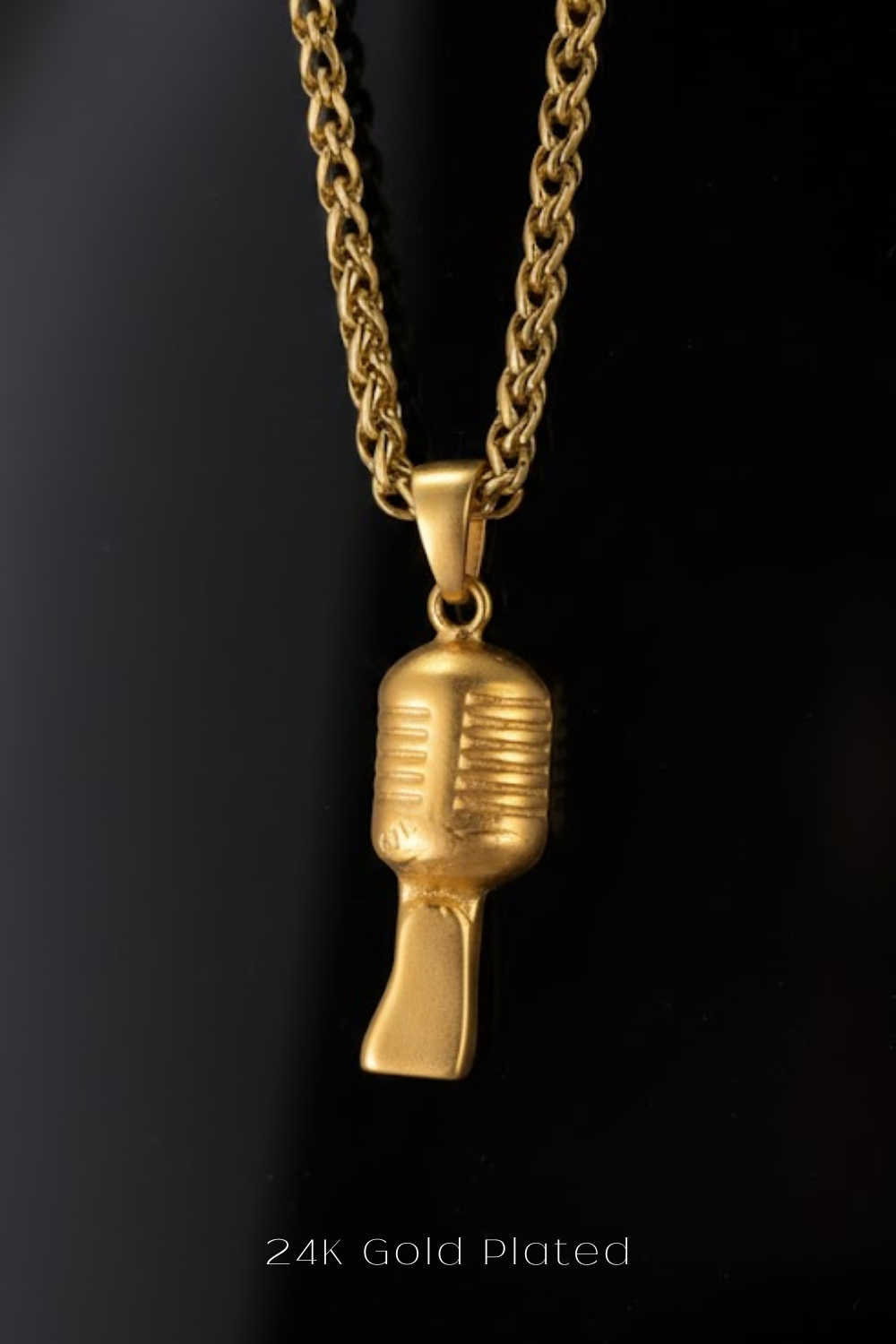 A gold-plated microphone pendant is displayed against a black background.