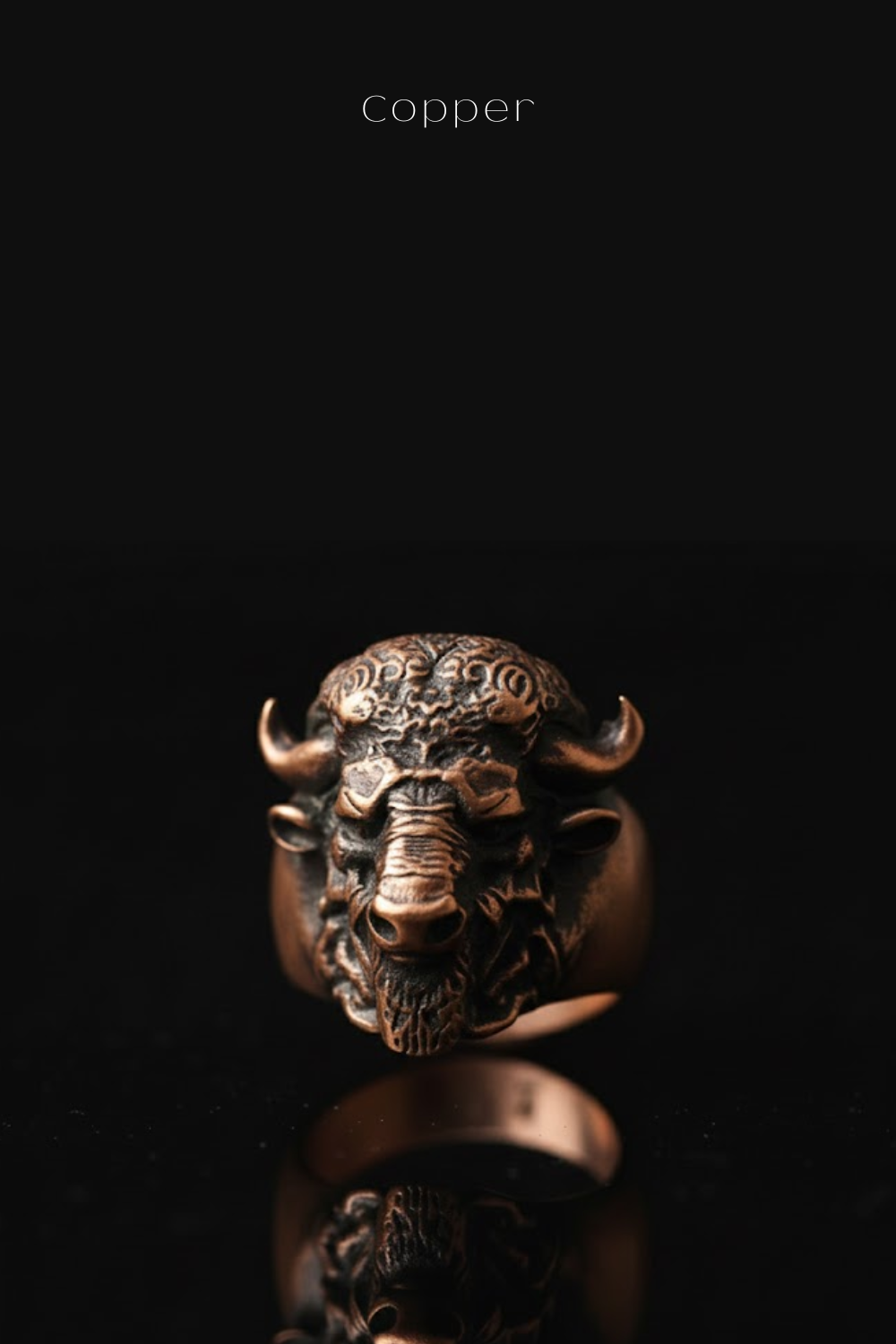 A close-up image of a detailed, intricately designed metal ring featuring a bull's head or buffalo head design.