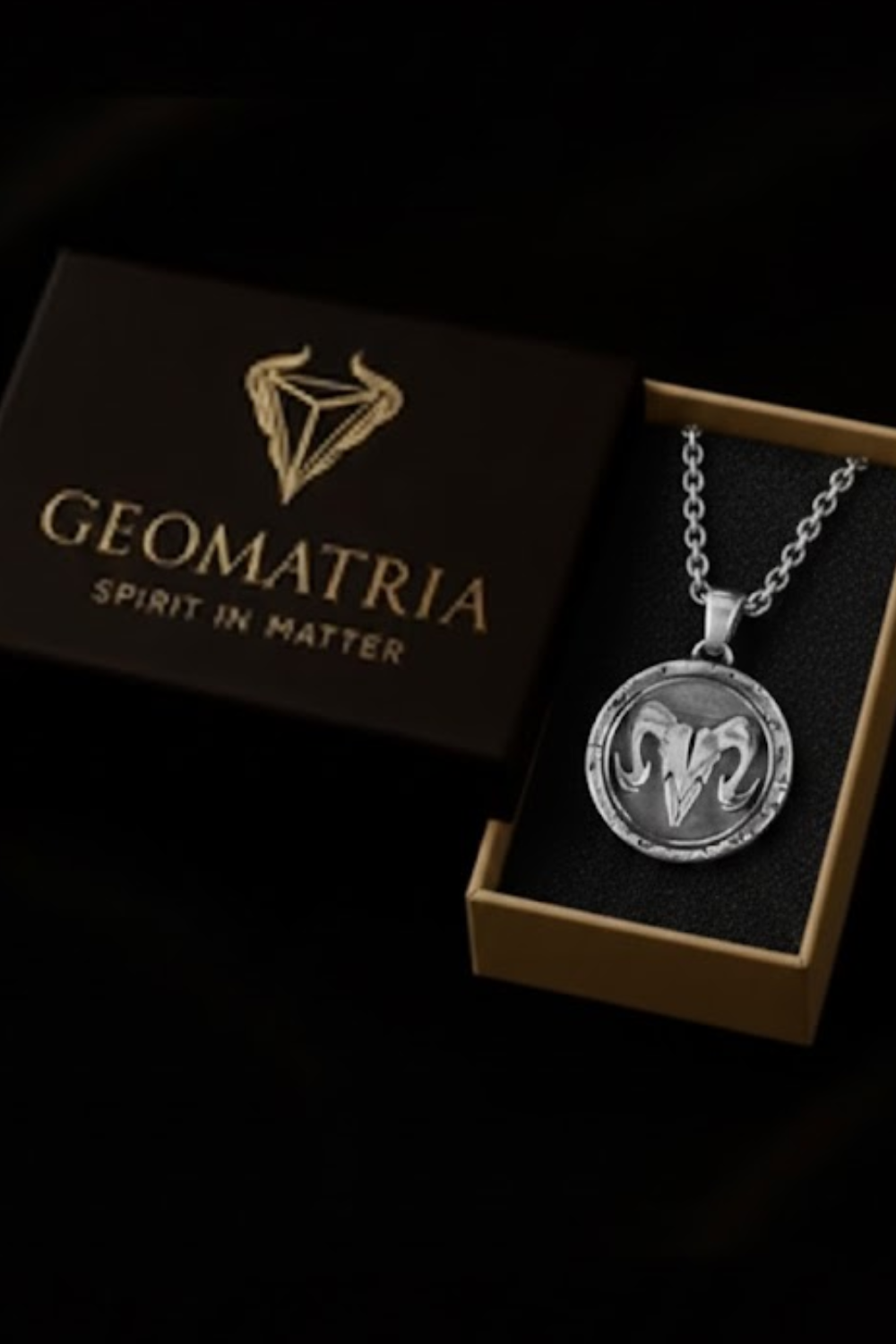 A necklace with a pendant is displayed in a box with the text "Geomatria Spirit in Matter" printed on it.