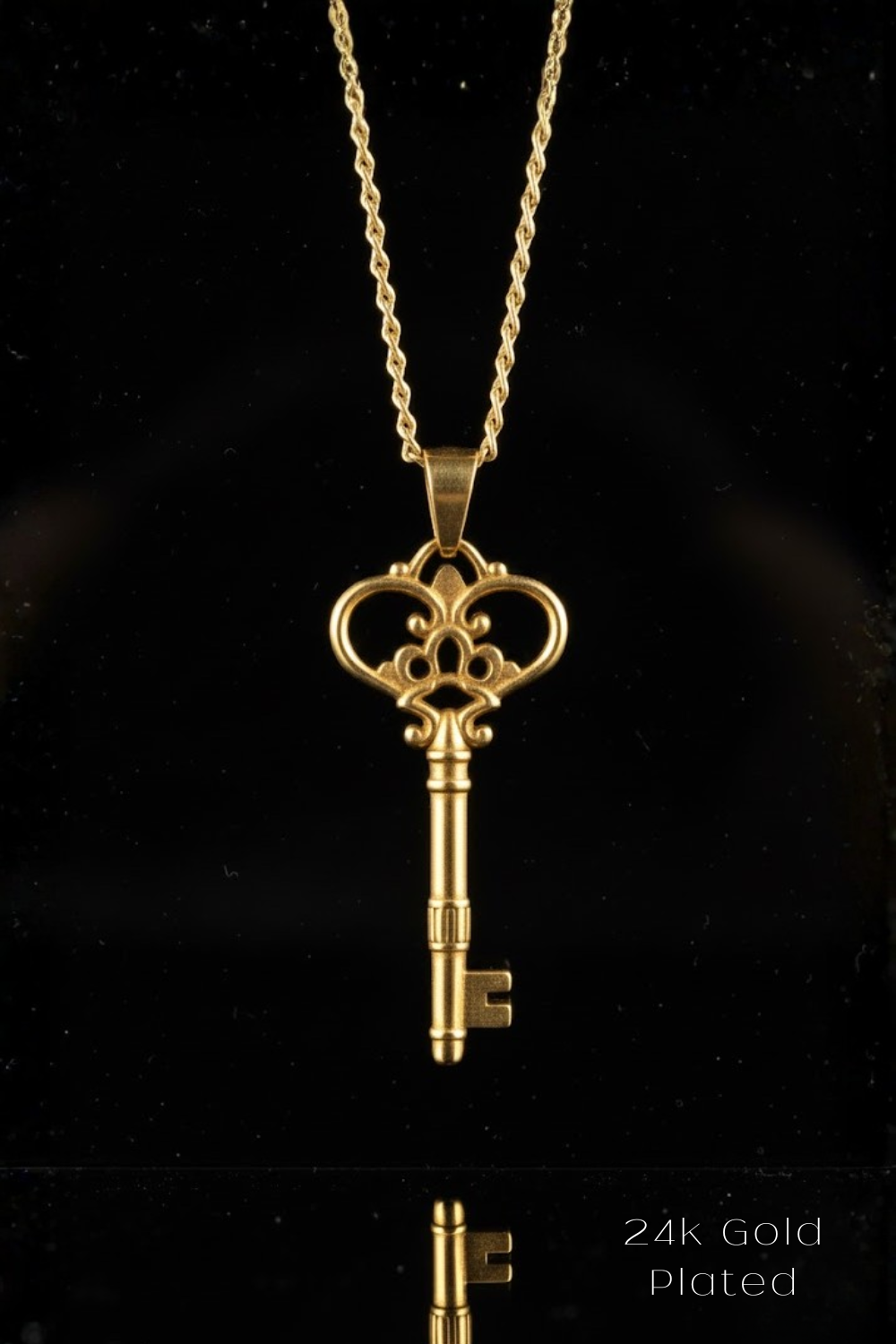 A 24k gold plated pendant featuring an ornate key design against a black background.