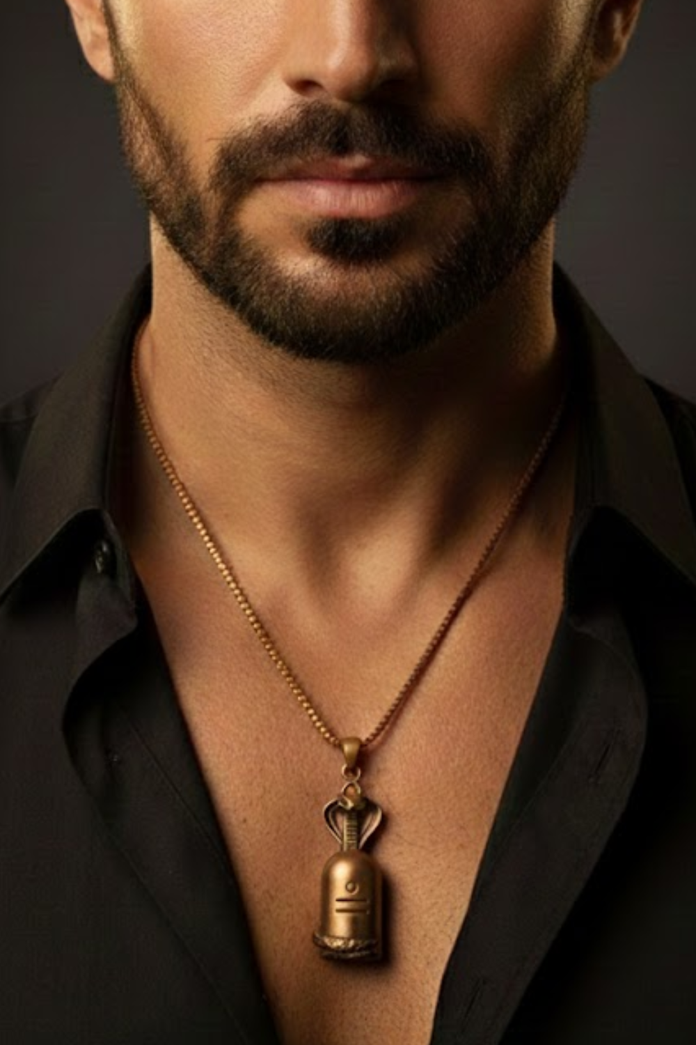A close-up of a man's neck and chest area, with a gold-colored pendant necklace visible.