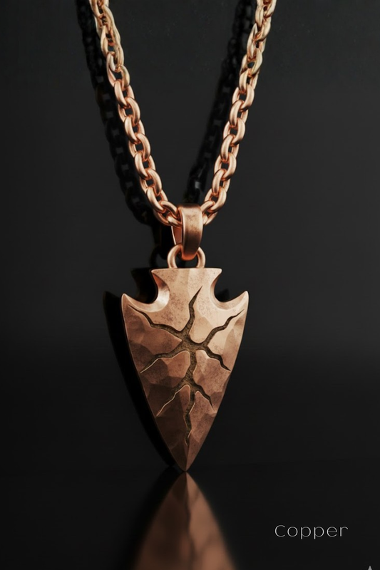 A copper-colored pendant necklace with a pointed arrow-shaped pendant featuring a cracked design.