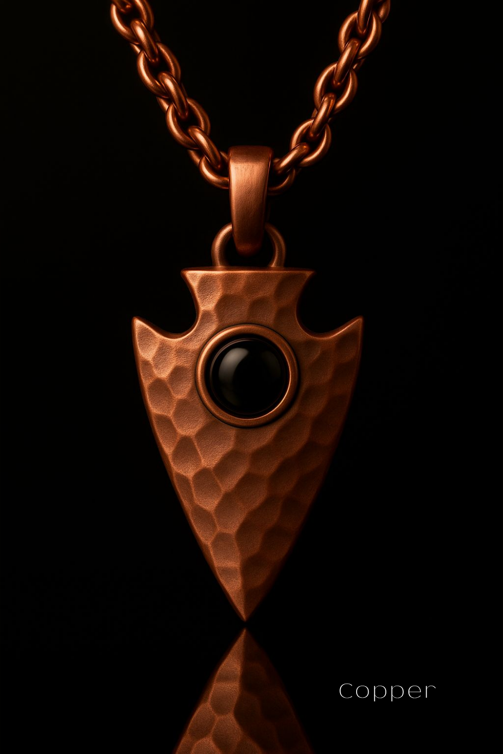 A copper-colored pendant with a black gemstone in the center, set against a black background.