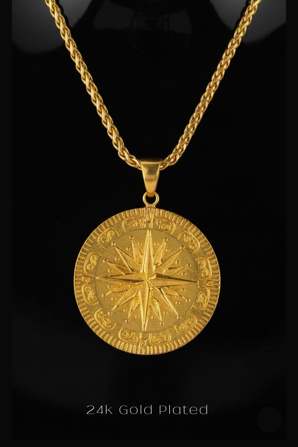 A 24k gold plated pendant necklace with a large circular medallion featuring a compass design.