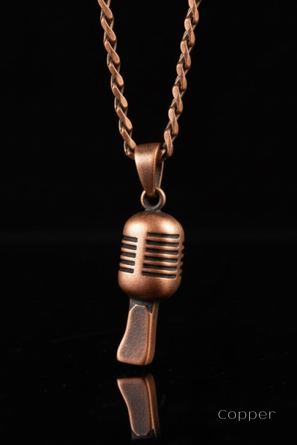 A copper-colored microphone pendant necklace against a black background.