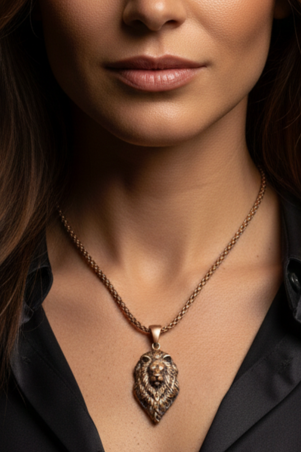 A close-up of a woman's neck and chest area, with a gold-colored pendant featuring a lion's head design hanging from a chain.