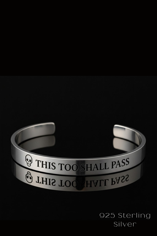 A silver bracelet with the text "THIS TOO SHARE PASS" engraved on it, against a black background.