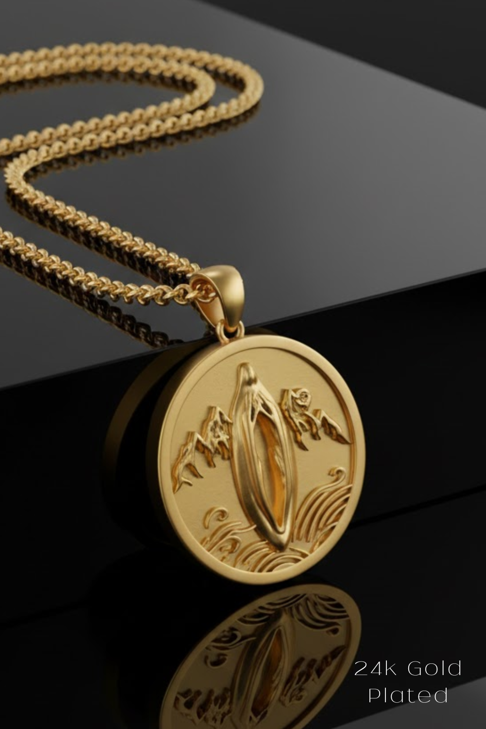 A gold-colored pendant necklace with a circular medallion featuring an embossed design, resting on a reflective surface.