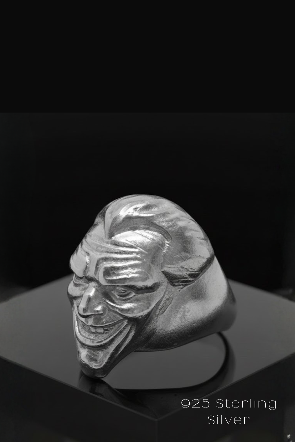 A silver ring in the shape of a smiling face, with a dark background.