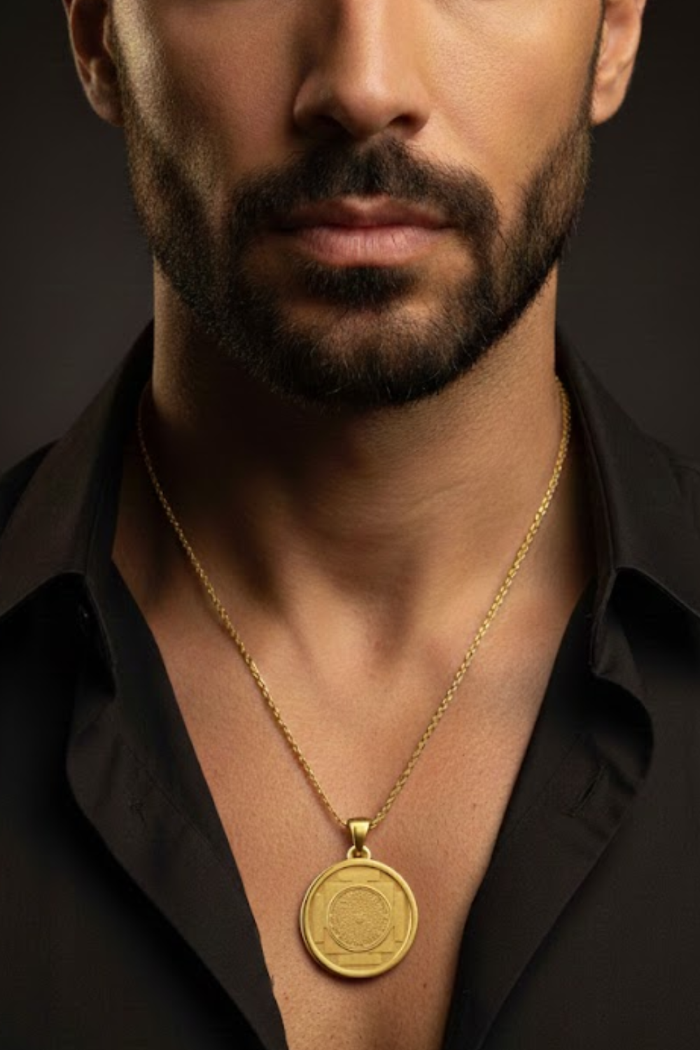 A close-up of a man's neck and chest area, with a gold necklace and a round pendant visible.