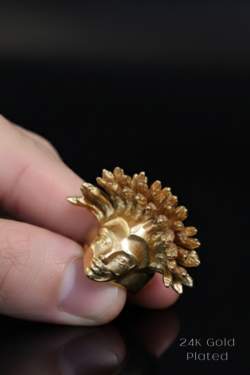 A close-up image of a person's hand holding a small, golden-colored metal object resembling a head or a face.