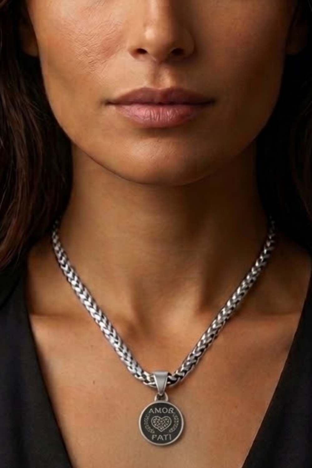 A close-up of a woman's neck and chest area, with a silver necklace featuring a pendant.