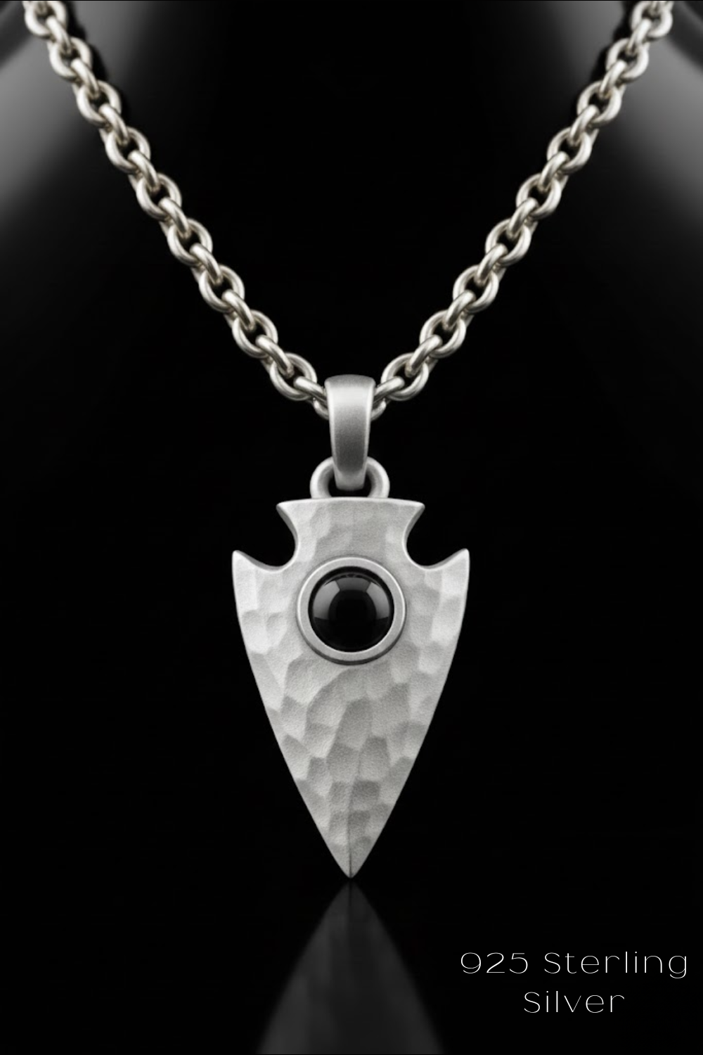 A silver pendant with a black stone in the center, set against a black background.