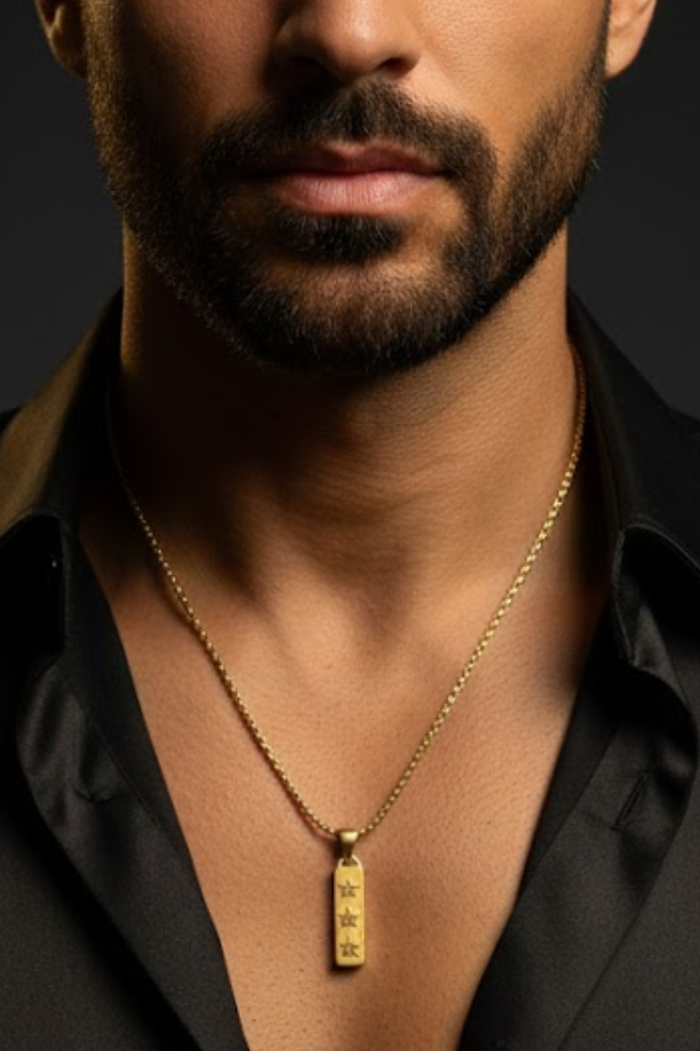 A close-up of a man's neck and chest area, with a gold necklace featuring a pendant with three stars.