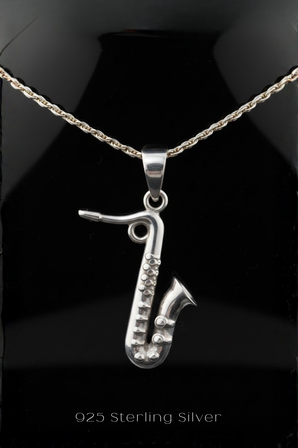 A silver saxophone pendant on a necklace.