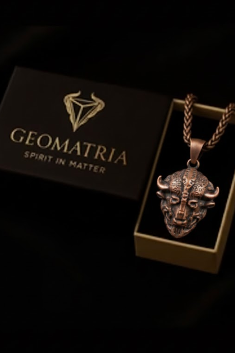 a pendant with a detailed metal design, displayed in a box with the text "Geomatria Spirit in Matter" printed on it.