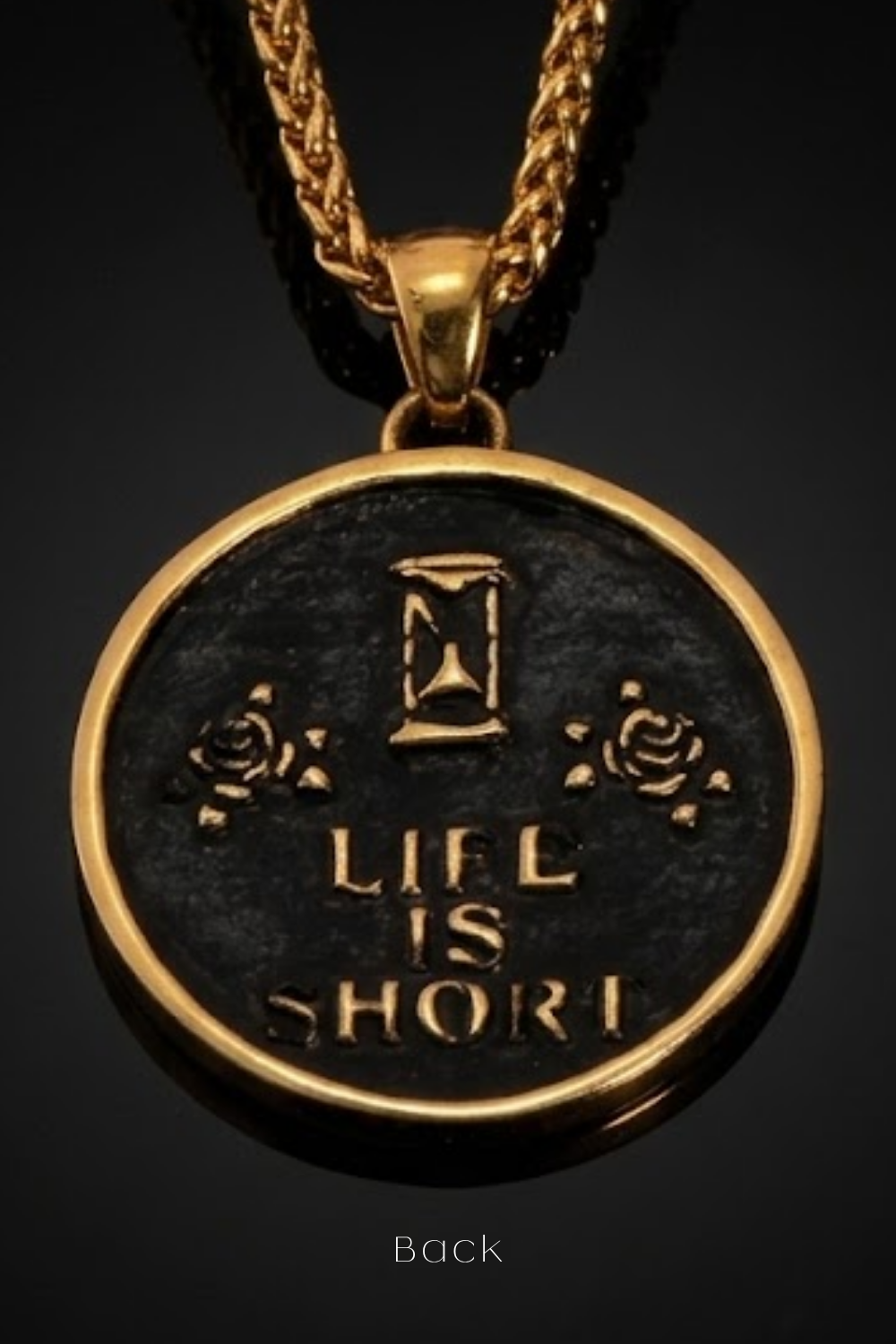 a pendant with the text "LIFE IS SHORT" engraved on it, along with a sand timer symbol.