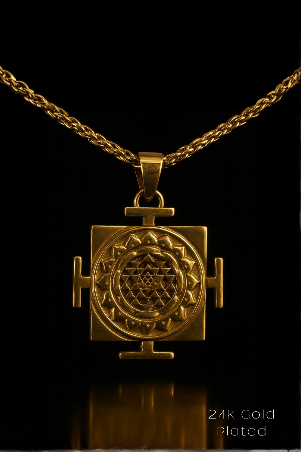 A gold-plated pendant with a geometric design, suspended from a chain against a black background.