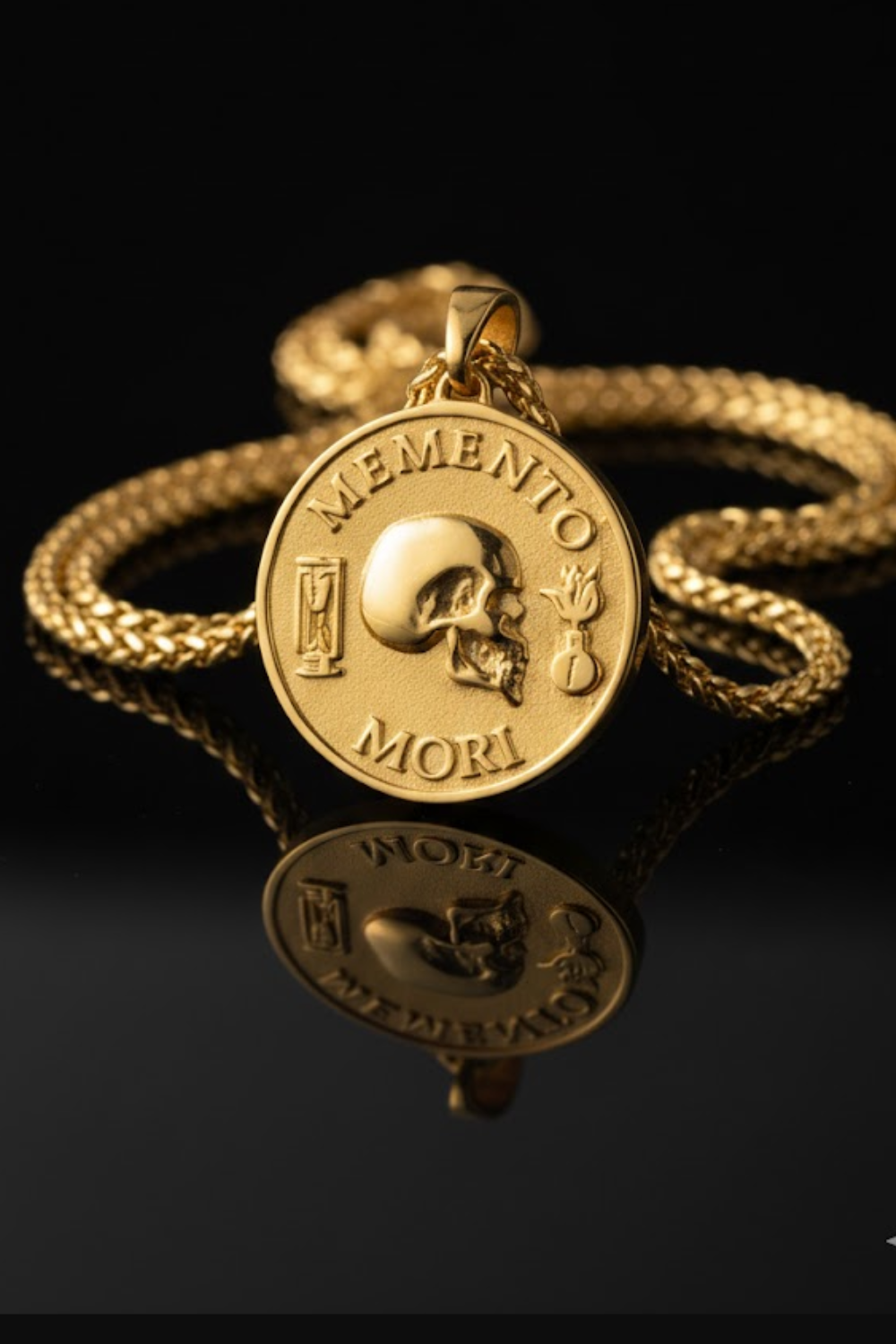 a gold-colored pendant with a skull design, accompanied by the Latin phrase "Memento mori" on a chain.