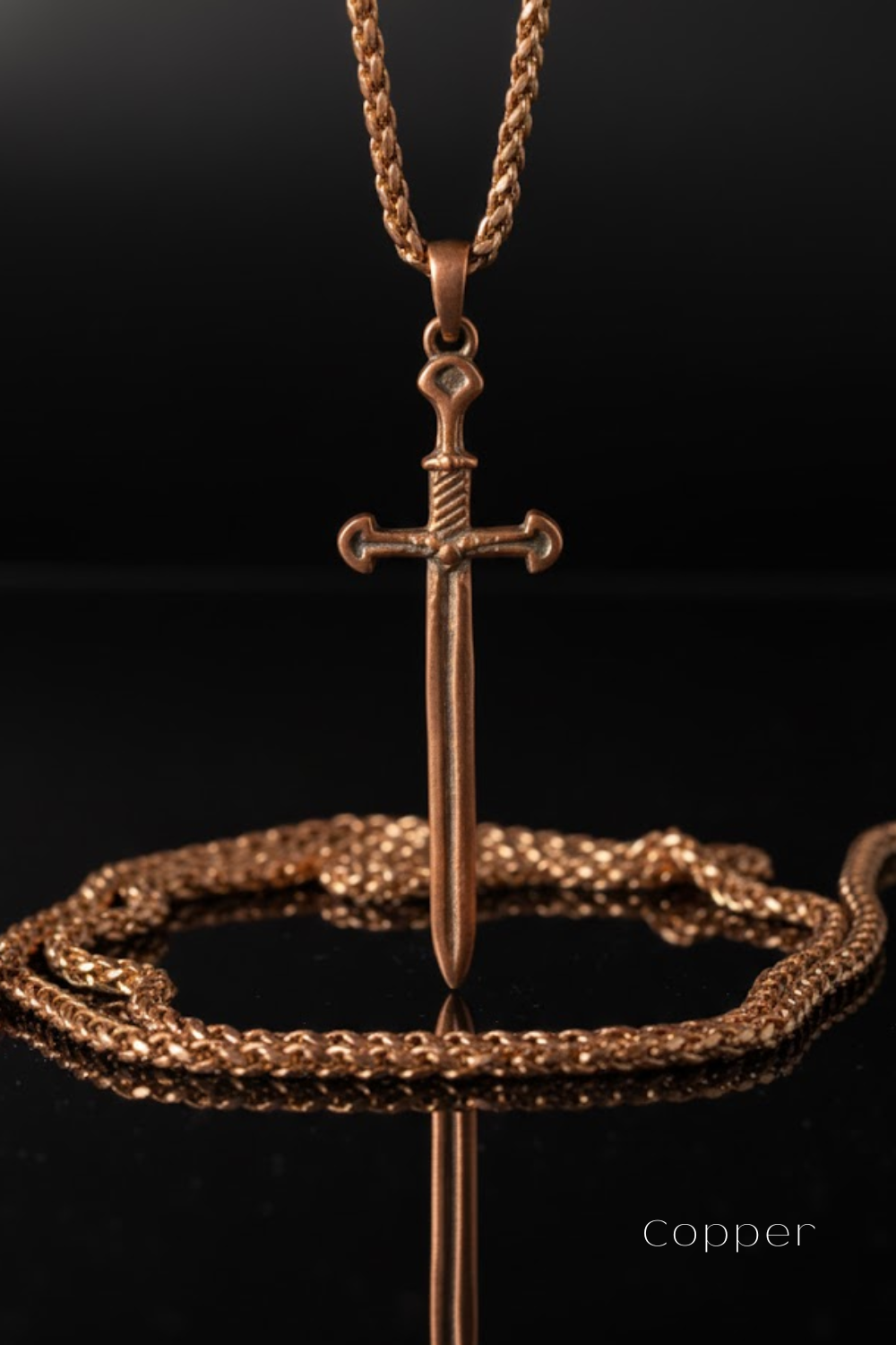 A copper-colored sword pendant with a chain necklace is displayed against a black background.
