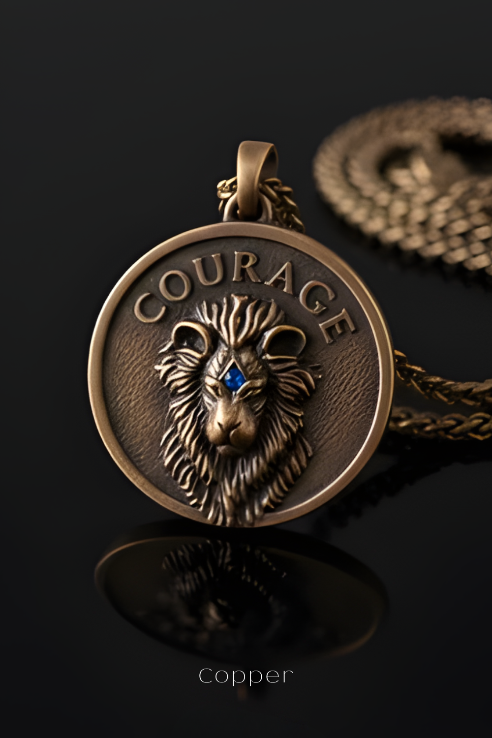 A close-up of a bronze pendant with a lion's head design, featuring the word "COURAGE" engraved on it.