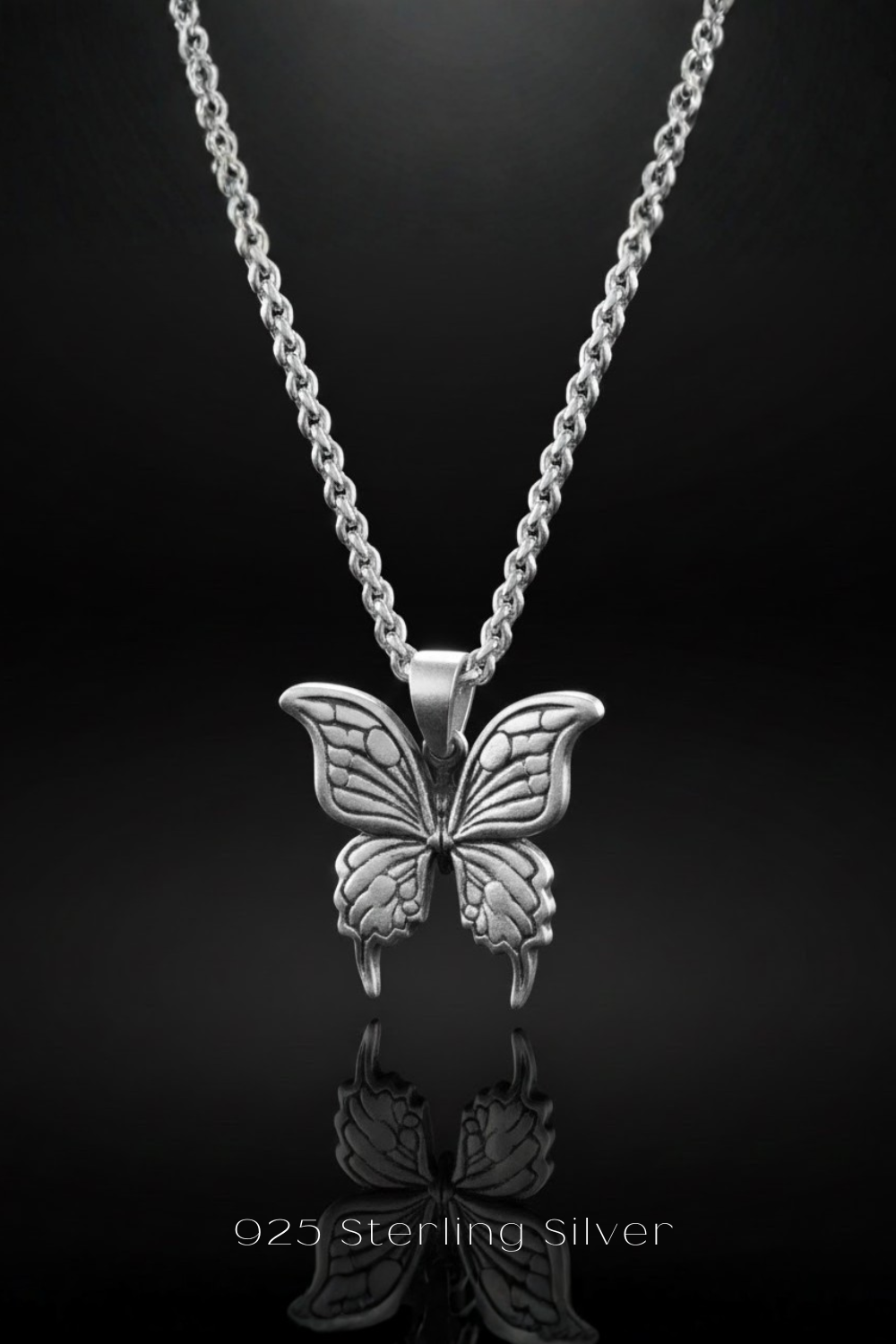 A silver butterfly pendant necklace against a black background.