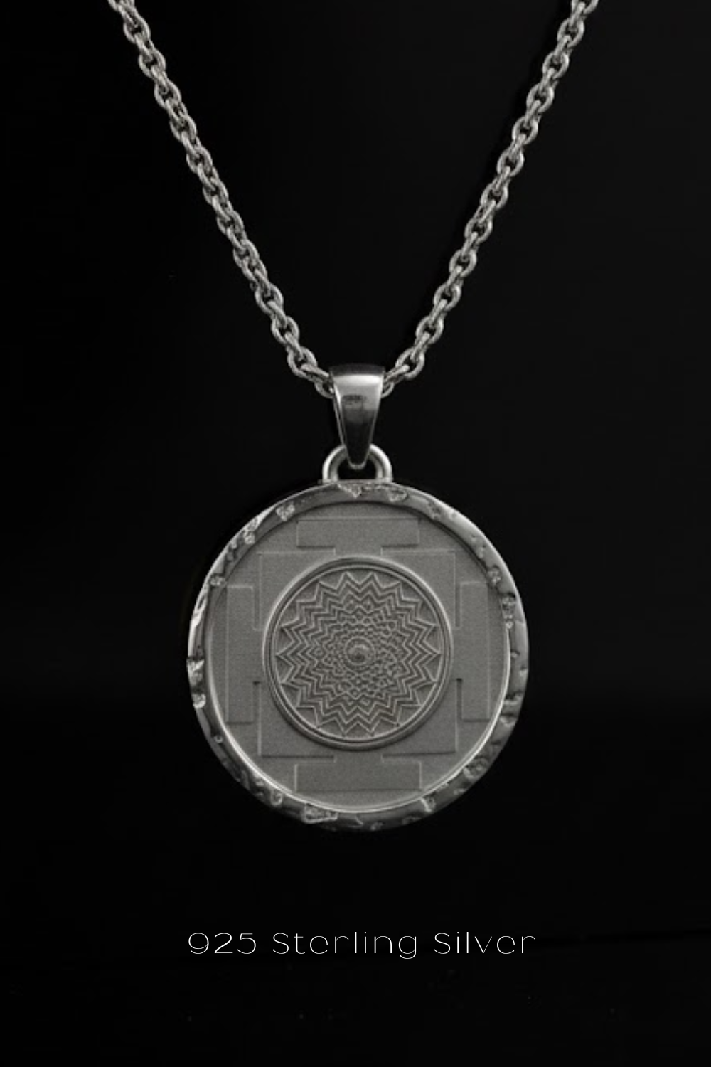 A silver pendant necklace with a circular medallion featuring a geometric design.