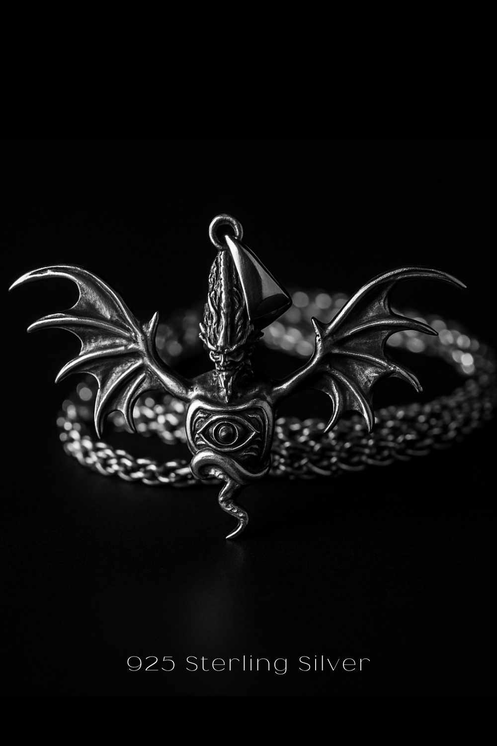 A silver pendant in the shape of a winged creature with a skull-like design, surrounded by a chain.