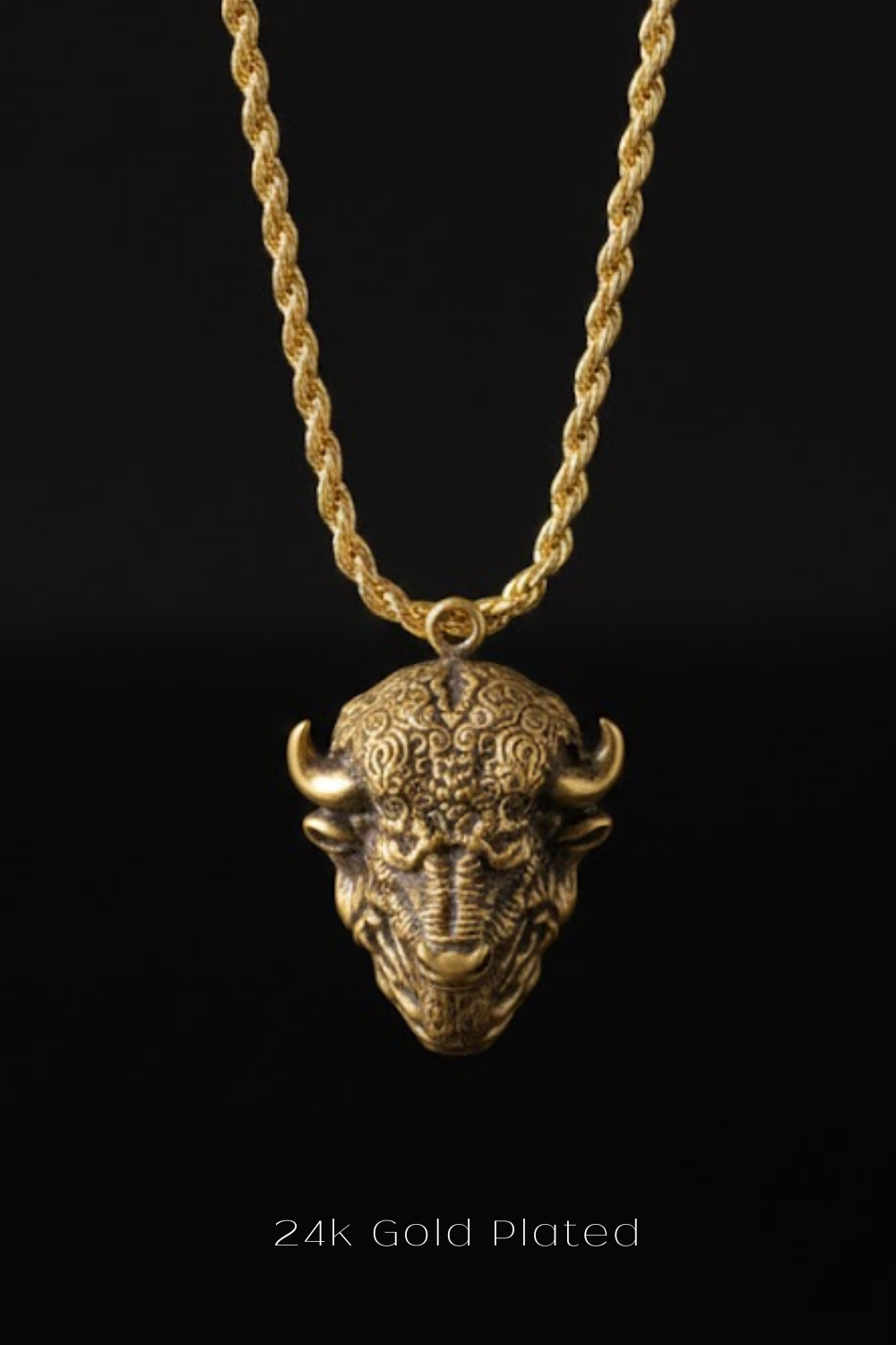 A 24k gold plated pendant in the shape of a buffalo head is displayed against a black background.