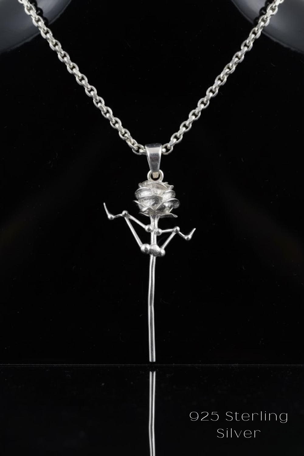 A silver necklace with a pendant featuring a stylized figure or design.