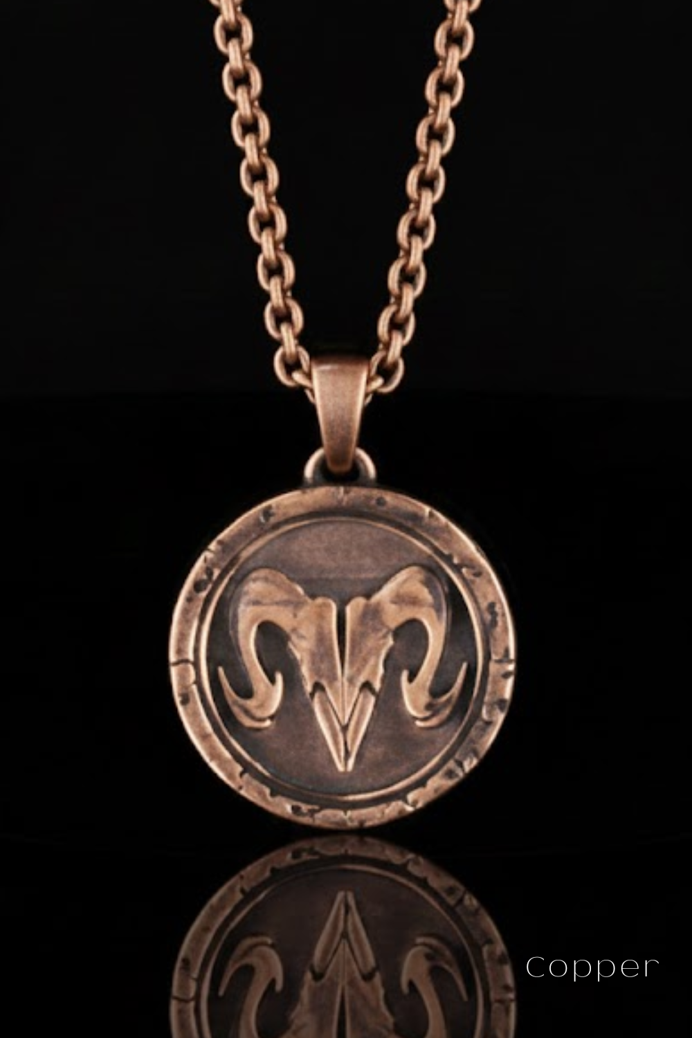 A copper-colored pendant necklace with a circular medallion featuring a ram's head design.