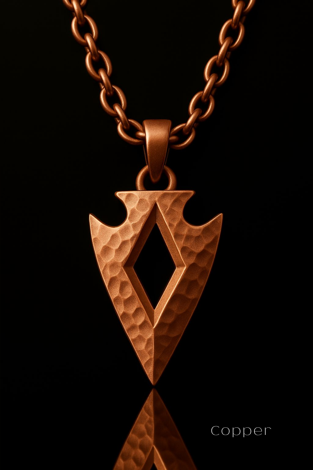 A copper-colored pendant with a textured, diamond-shaped design is suspended from a chain against a black background.