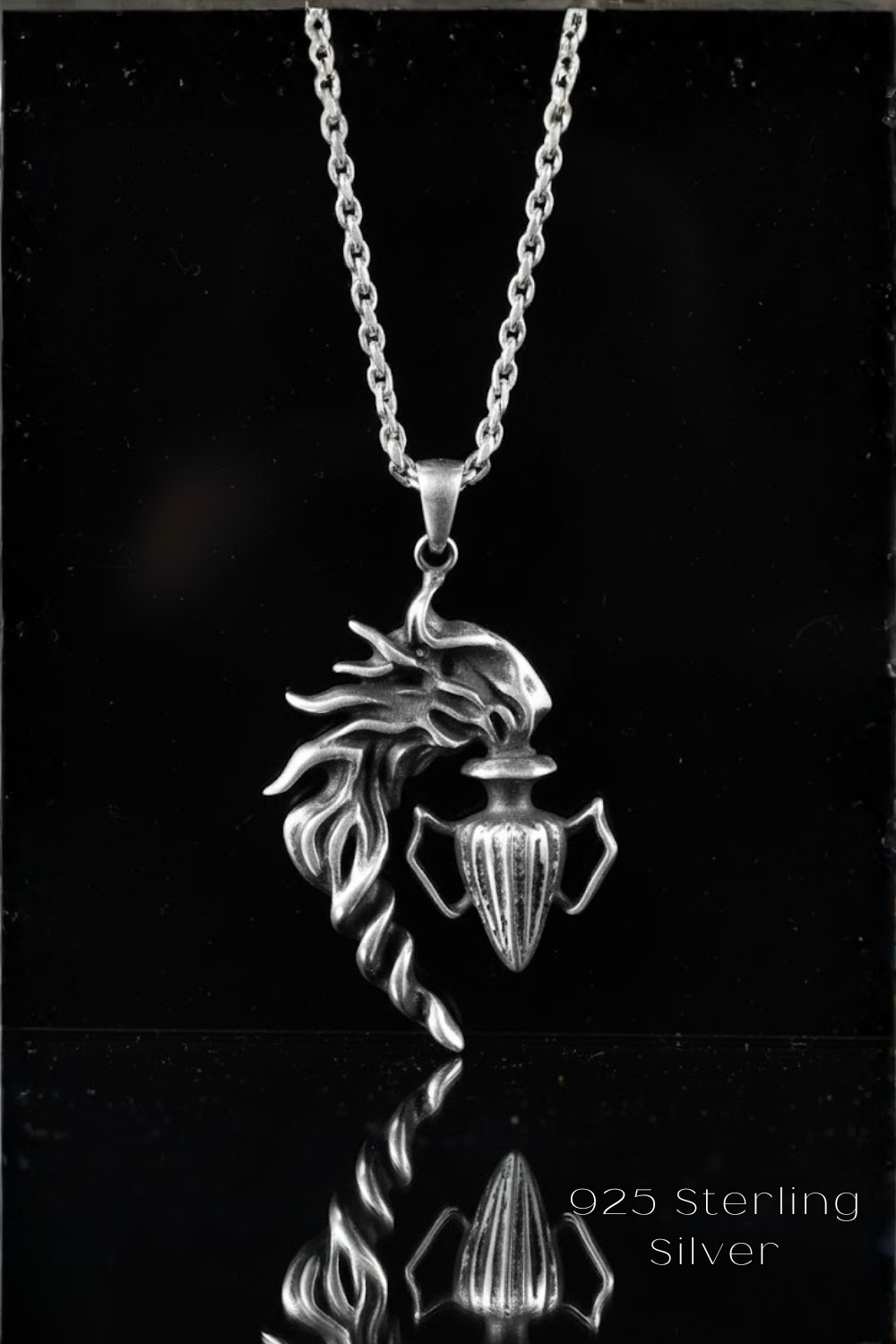 A silver pendant necklace with a detailed design, including a stylized fish or aquatic creature and a vase-like container.
