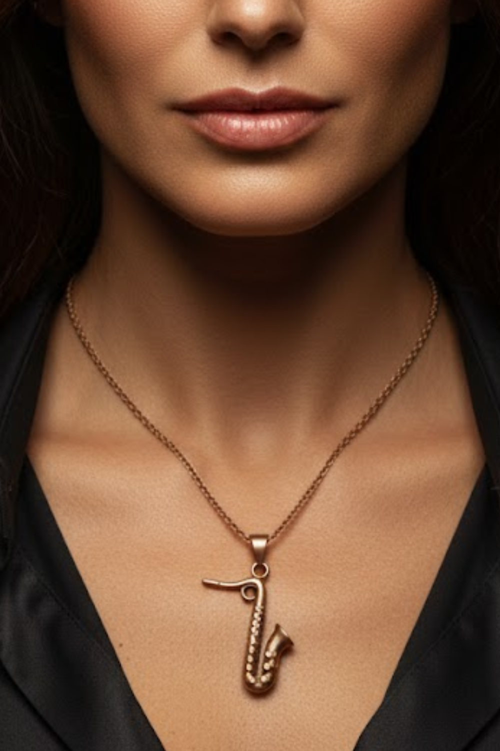 A close-up of a woman's neck and chest area, with a gold-colored necklace featuring a pendant in the shape of a saxophone.