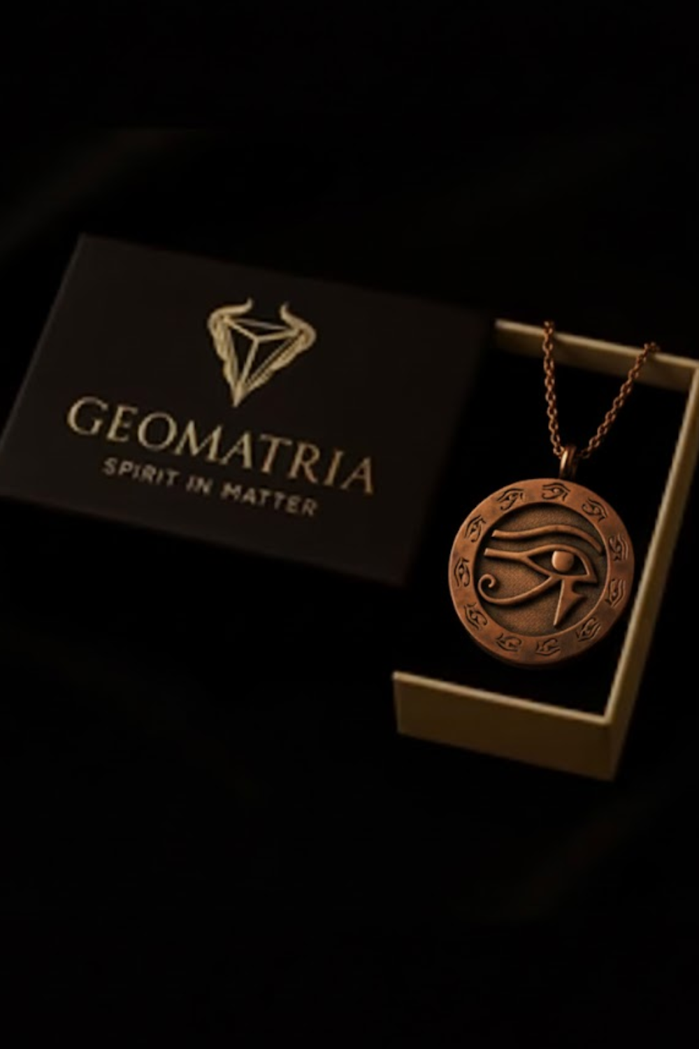 a pendant necklace with an eye design, placed inside a black box with the word "Geomatria" printed on it.